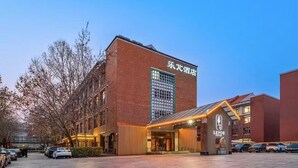 A hotel with a prominent entrance, a large sign, and a parking area. - Le Peng hotel (Tianjin)
