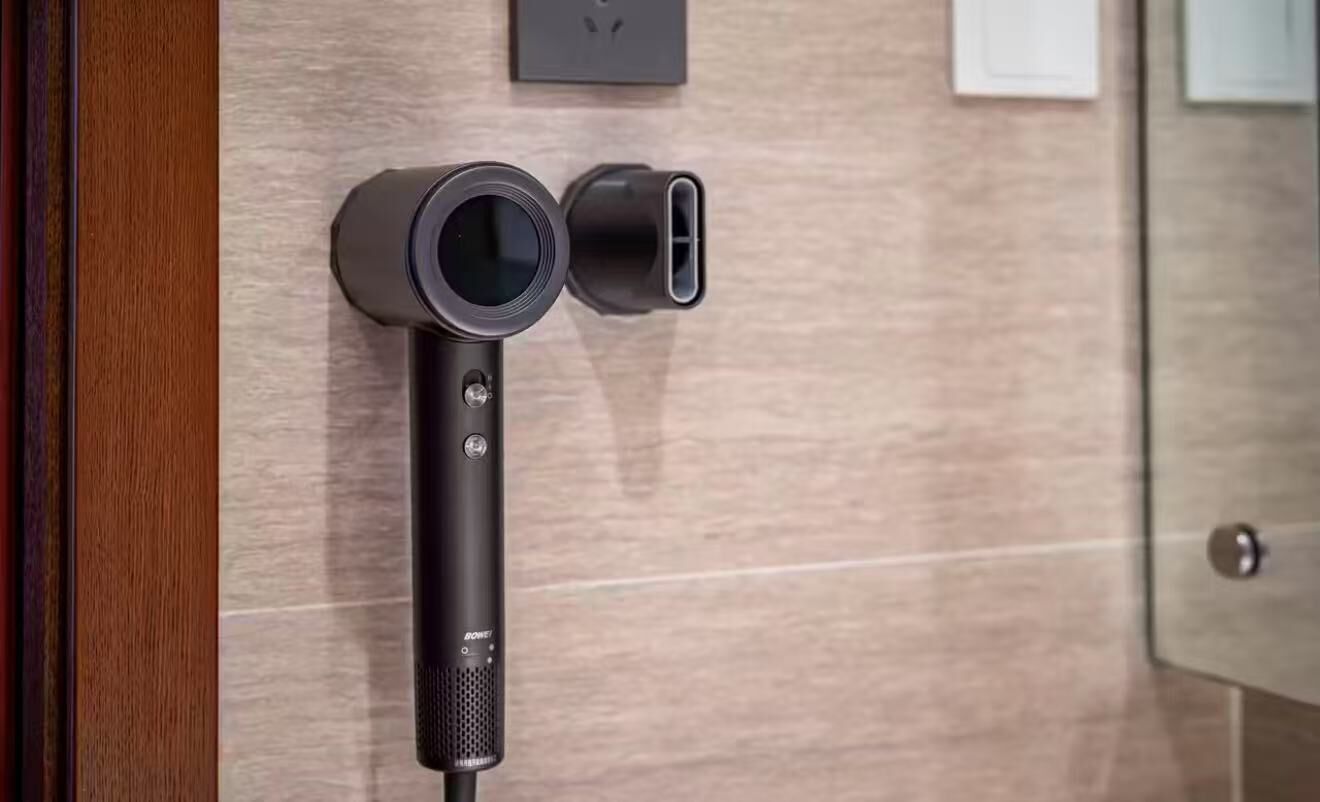 A wall-mounted device with a circular lens and a rectangular port, likely a security or surveillance camera.