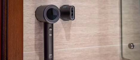 A wall-mounted device with a circular lens and a rectangular port, likely a security or surveillance camera.
