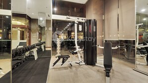 Een moderne sportschool met gewichthefapparatuur, een bank en een spiegelwand.