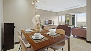 Een moderne eetruimte met een houten tafel voor vier personen, een zwarte koelkast en een groot raam met uitzicht.