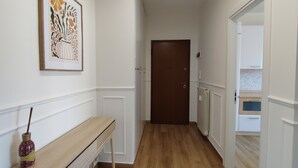 Un couloir avec un banc en bois, une œuvre d’art encadrée et une porte au fond.