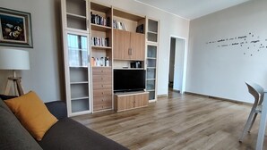 Un salon avec un canapé, un téléviseur et une bibliothèque.