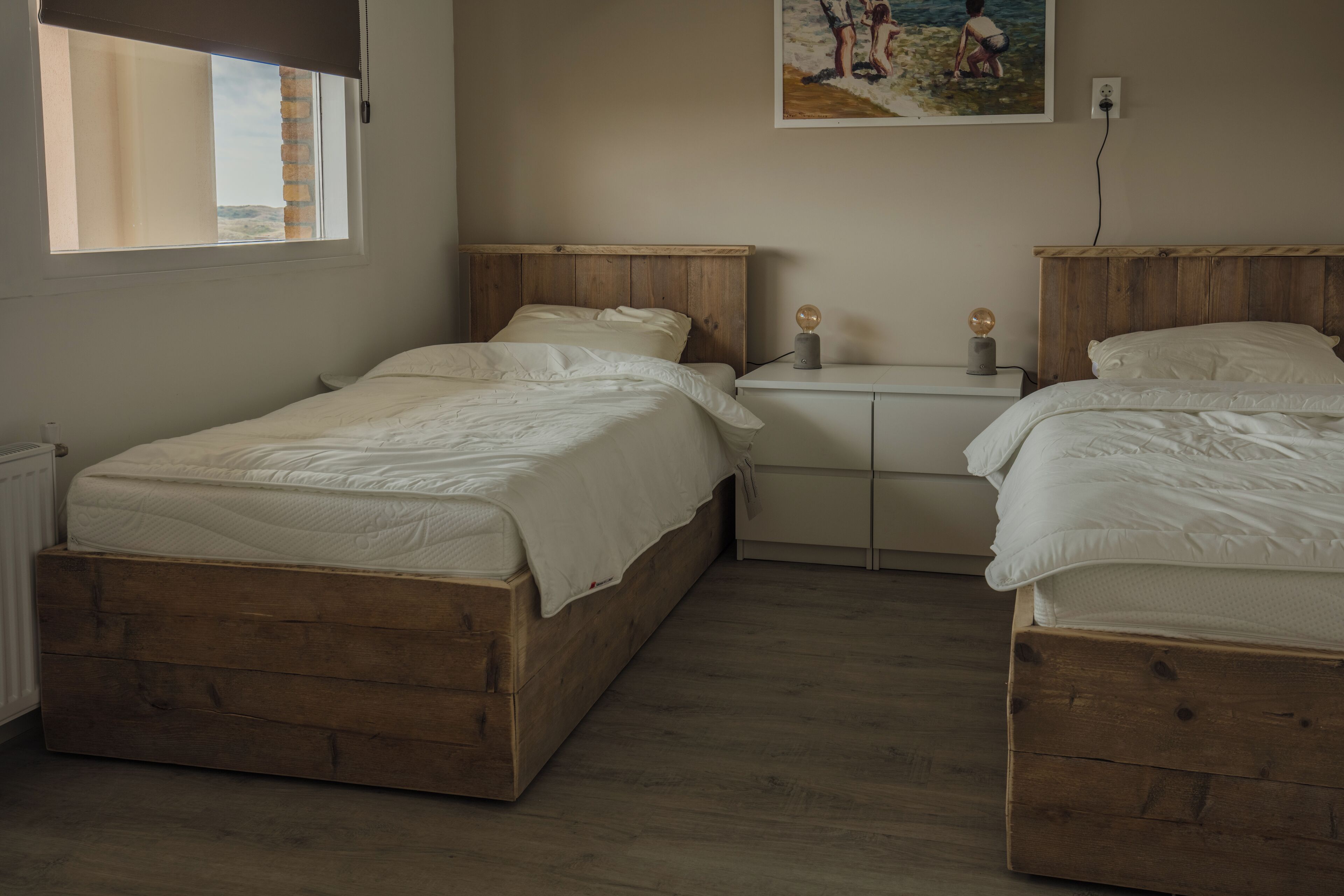 Une chambre à coucher avec deux lits en bois, une table de chevet et une lampe fixée au mur.