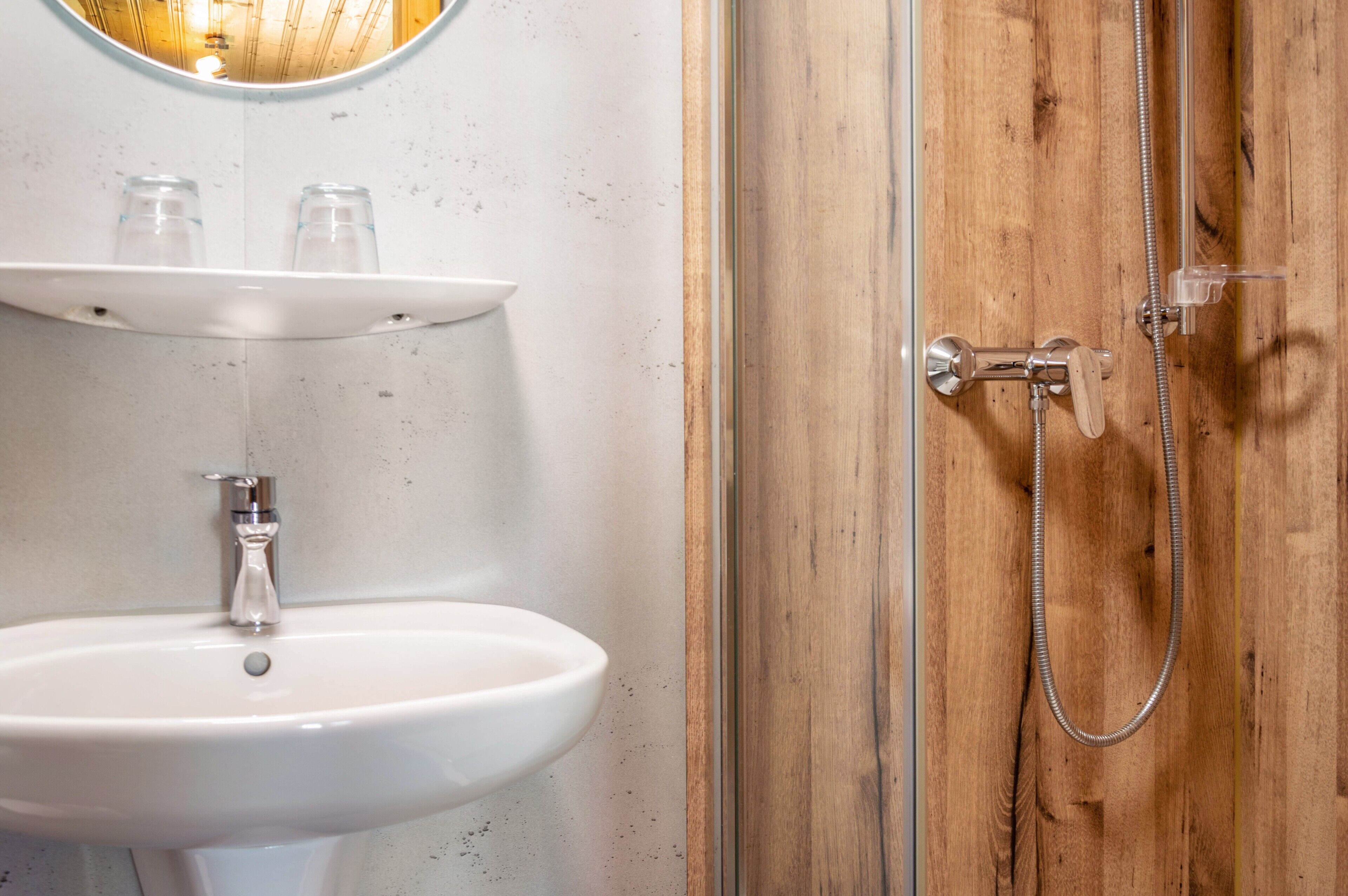 Une salle de bain avec un lavabo blanc, un miroir et une porte en bois.
