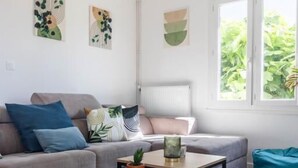 A modern living room with a grey sofa, a wooden coffee table, and a teal bean bag. - CosyFamily 1st floor-Pool-Wifi-Family-Plage (Pérols)