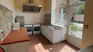 A kitchen with a red countertop, white cabinets, and a window with a view of greenery outside. - Group gîte, many activities, river, footbridge, dogs ok, nature (Mazamet)