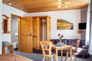A wooden-paneled room with a dining table, chairs, a sofa, and a television. - Room 'Lutz - Zimmer 2' with Shared Terrace, Shared Garden and Wi-Fi (Iphofen)