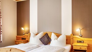 A wooden bed with white bedding, two bedside tables, and wall-mounted lamps. - Room 'Lutz - Zimmer 2' with Shared Terrace, Shared Garden and Wi-Fi (Iphofen)