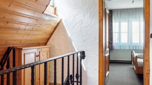 A wooden staircase with a black railing leading to a room with a bed and a window with curtains. - Room 'Lutz - Zimmer 3' with Shared Terrace, Shared Garden and Wi-Fi (Iphofen)