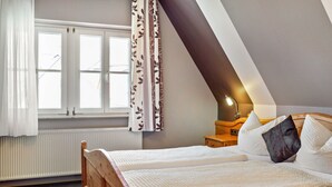 A bedroom with a bed, a nightstand, a lamp, and a window with curtains. - Room 'Lutz - Zimmer 3' with Shared Terrace, Shared Garden and Wi-Fi (Iphofen)