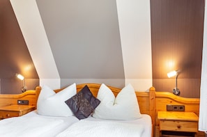 Ein Schlafzimmer mit einem hölzernen Kopfteil, zwei Nachttischen, einem Bett mit weißer Bettwäsche und zwei Wandleuchten.