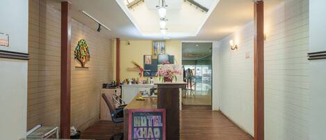 A hotel lobby with a skylight, a reception desk, and a sign indicating the hotel's location.