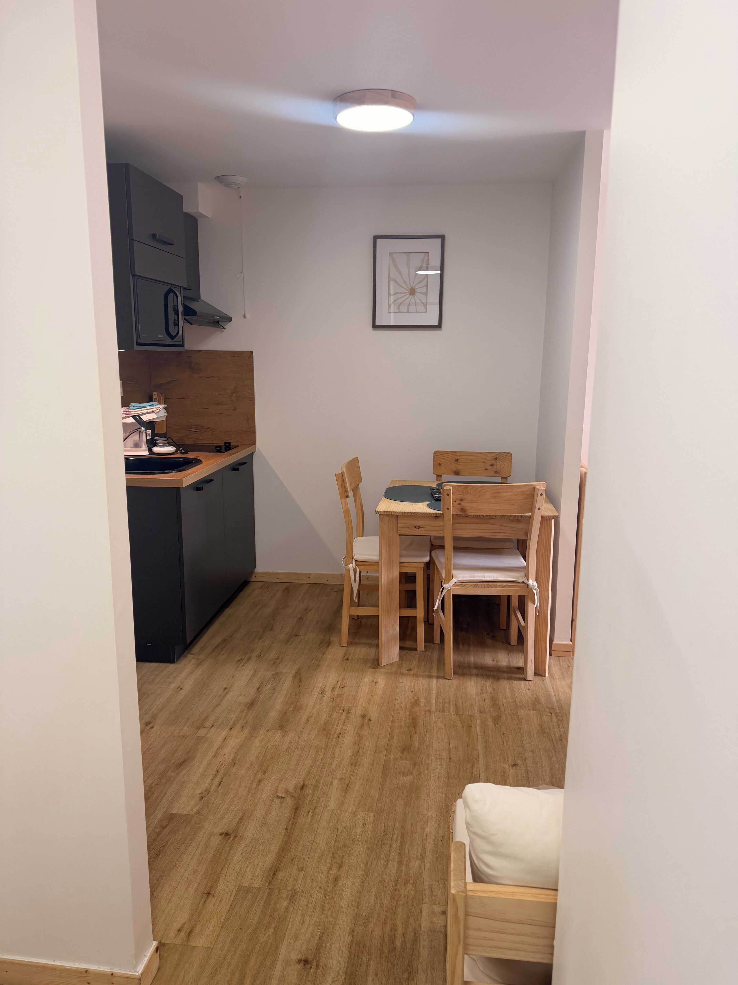 Une cuisine de taille réduite avec un coin repas, des meubles en bois et un luminaire au plafond.