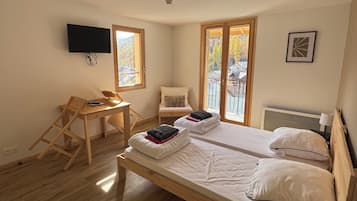 A room with a bed, a chair, a desk, a TV, and a window with a view.