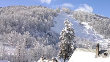 A snowy mountain landscape with a ski slope, snow-covered trees, and buildings with snow on their roofs.
