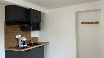 A modern kitchen with black cabinets, a wooden countertop, and a built-in microwave.