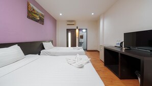 Ein Hotelzimmer mit zwei Betten, einem Fernseher, einem Schreibtisch und einem Bild an der Wand.