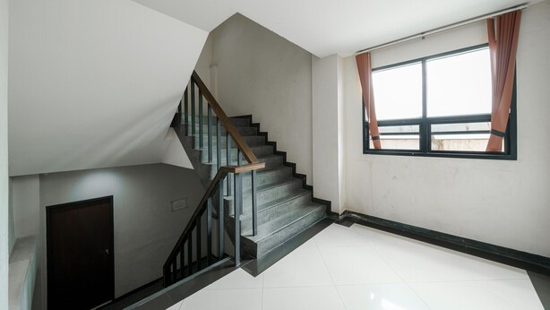 A staircase with a wooden handrail and black steps leading to a landing.