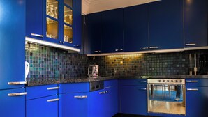 Una cocina moderna con armarios azules, horno de acero inoxidable y salpicadero de azulejos.