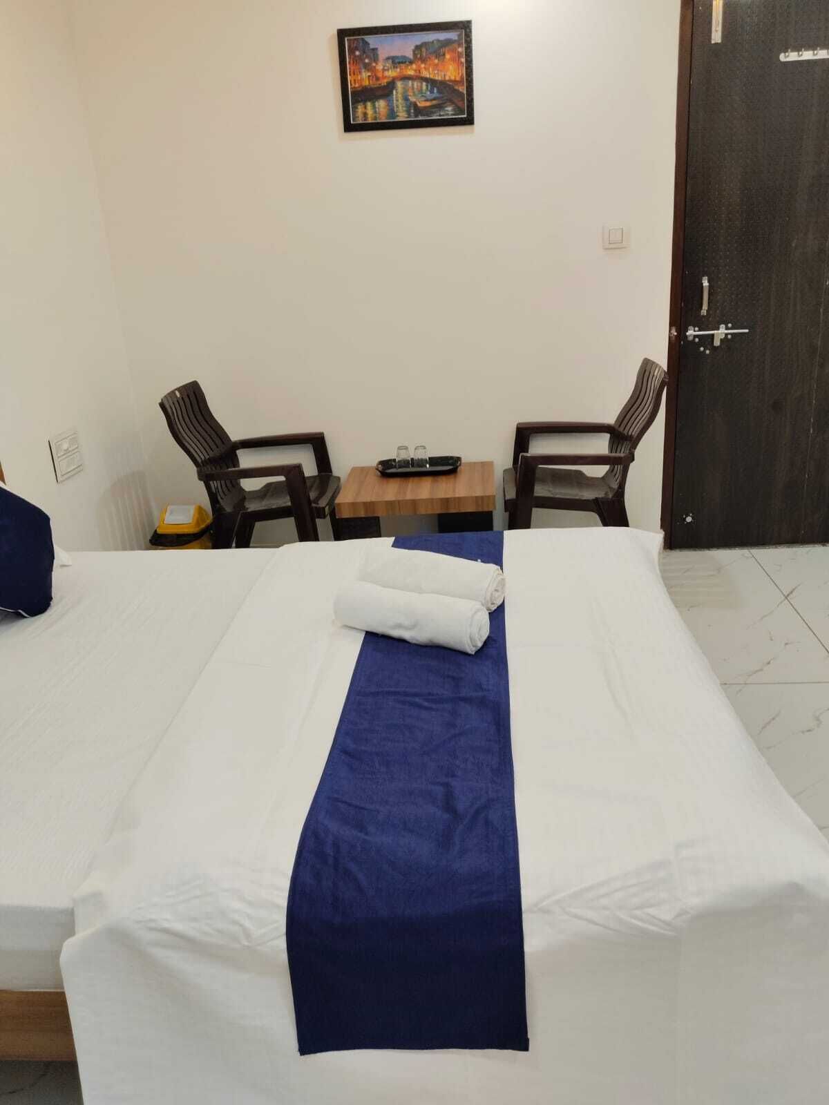 A hotel room with a bed, two chairs, a small table with a tray, and a door.