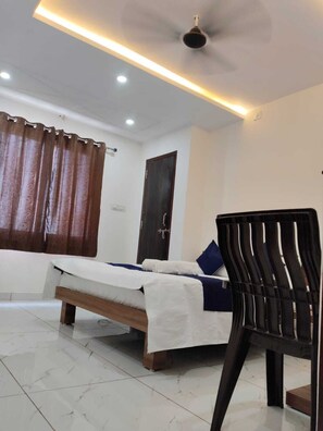 Um quarto com uma cama, uma cadeira, um ventilador de teto e uma porta.