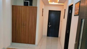 A hallway with a wooden wardrobe, a reception desk, and a black door at the end. - Hotel Bhavya Palace (Udaipur)