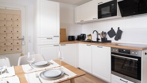 Une cuisine moderne avec des armoires blanches, un plan de travail en bois, un four à micro-ondes, une cuisinière et un calendrier accroché au mur.