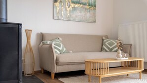 Un salon avec un canapé, une table basse en bois, un lampadaire et un tableau accroché au mur.