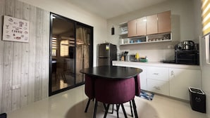 A compact kitchen with a dining area, a refrigerator, and a coffee machine.