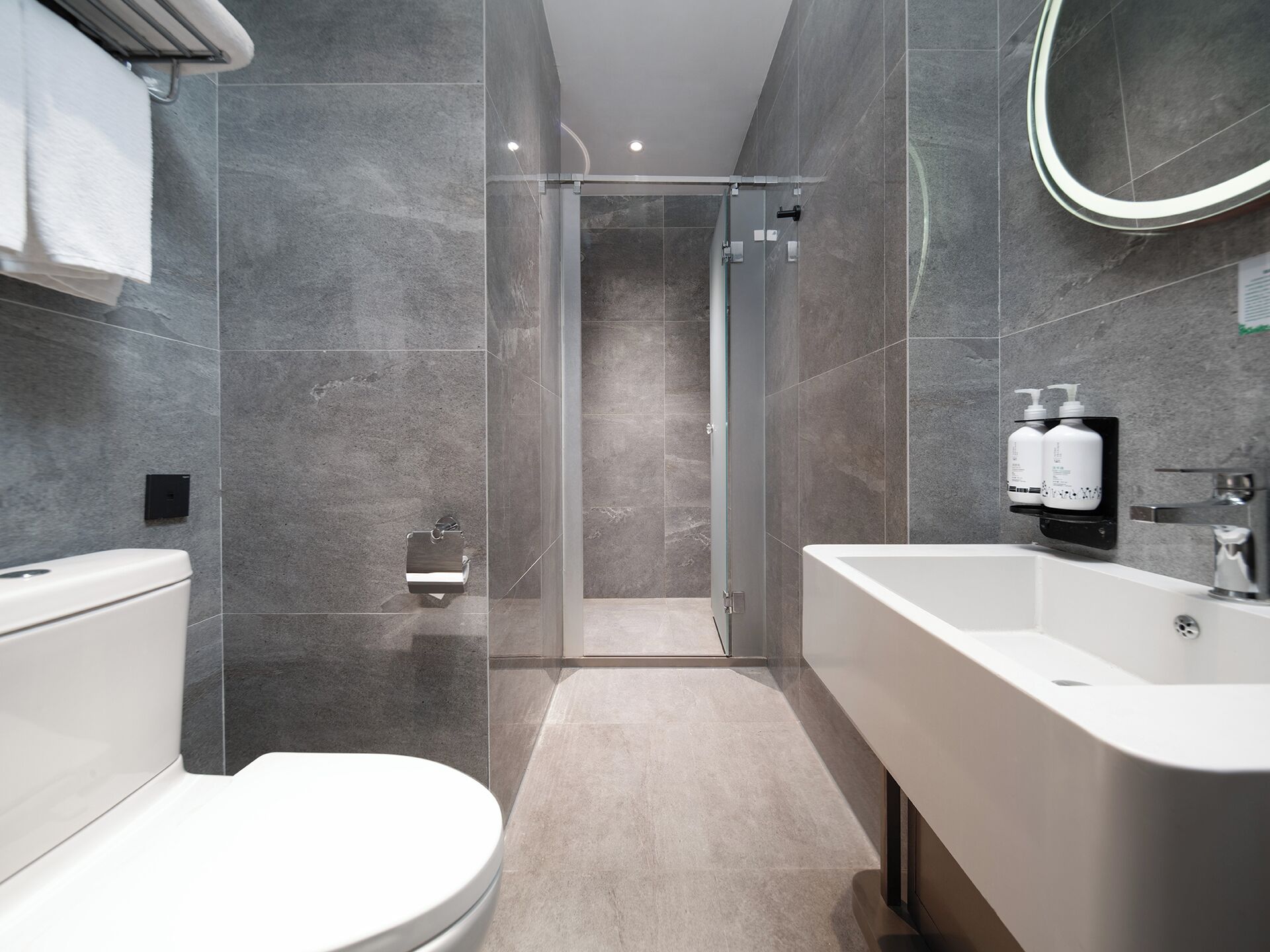 Ein modernes Badezimmer mit Toilette, Duschkabine und großzügigem Waschbecken.
