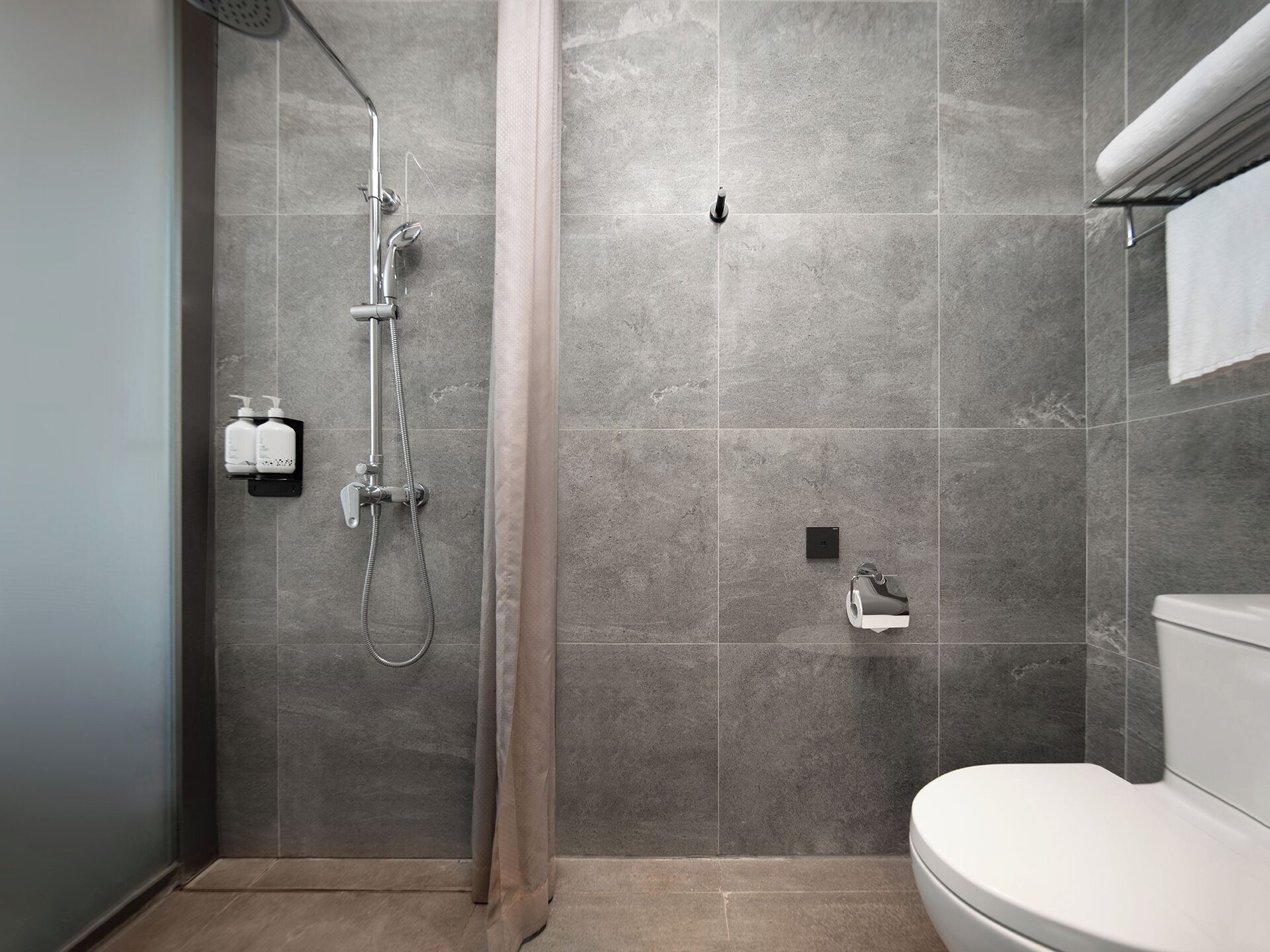 Een moderne badkamer met douche, toilet en handdoekrek.
