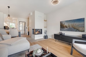 Een moderne woonkamer met een open haard, een eethoek en een groot raam.