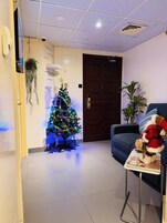 A reception area with a Christmas tree, a blue armchair, and a Santa Claus decoration.