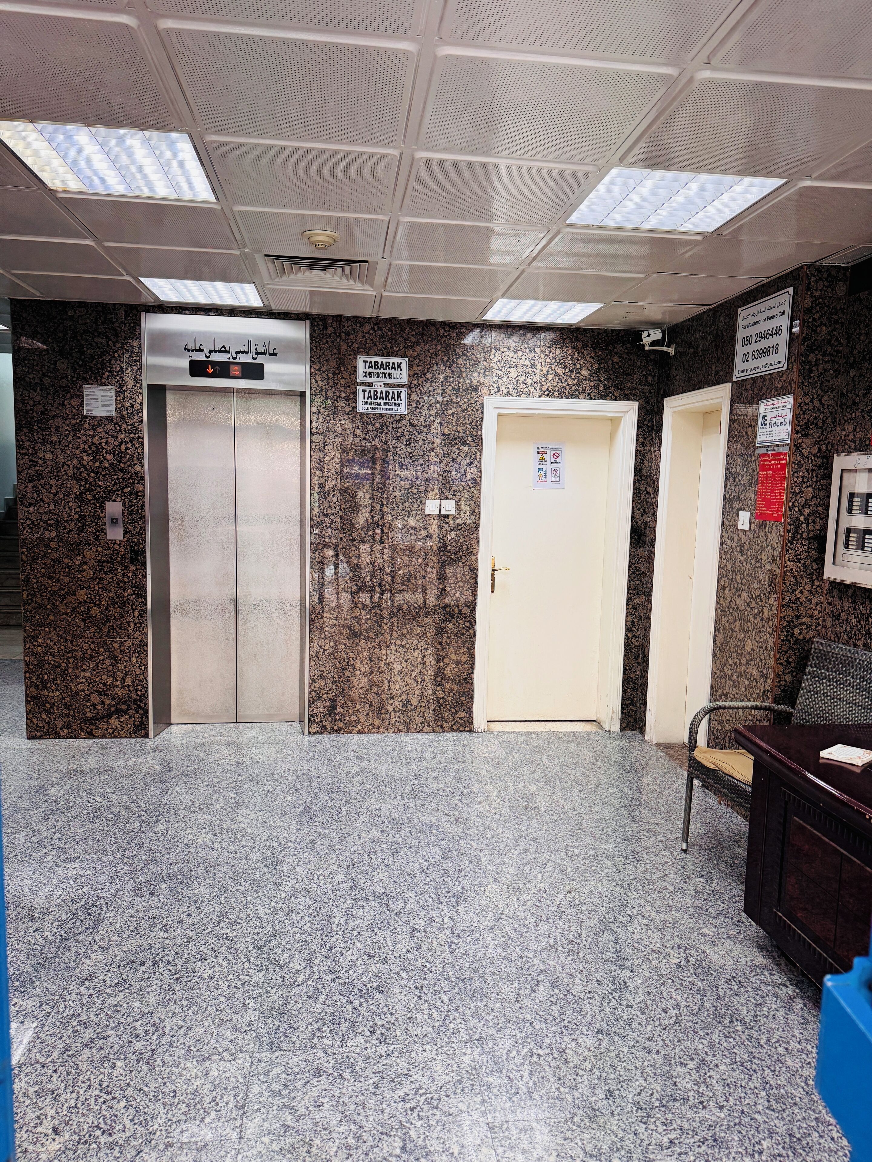 An elevator area with granite walls, a reception desk, and a door with a sign.
