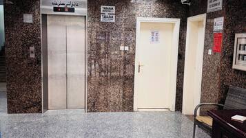 An elevator area with granite walls, a reception desk, and a door with a sign.