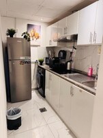 A modern kitchen with white cabinets, a stainless steel refrigerator, a built-in oven, and a sink.