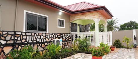 A house with a stone facade, a tiled patio, and a covered porch area.