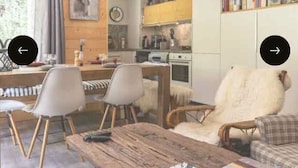 Una sala de estar acogedora con una mesa de centro de madera, un sofá y un comedor con sillas.