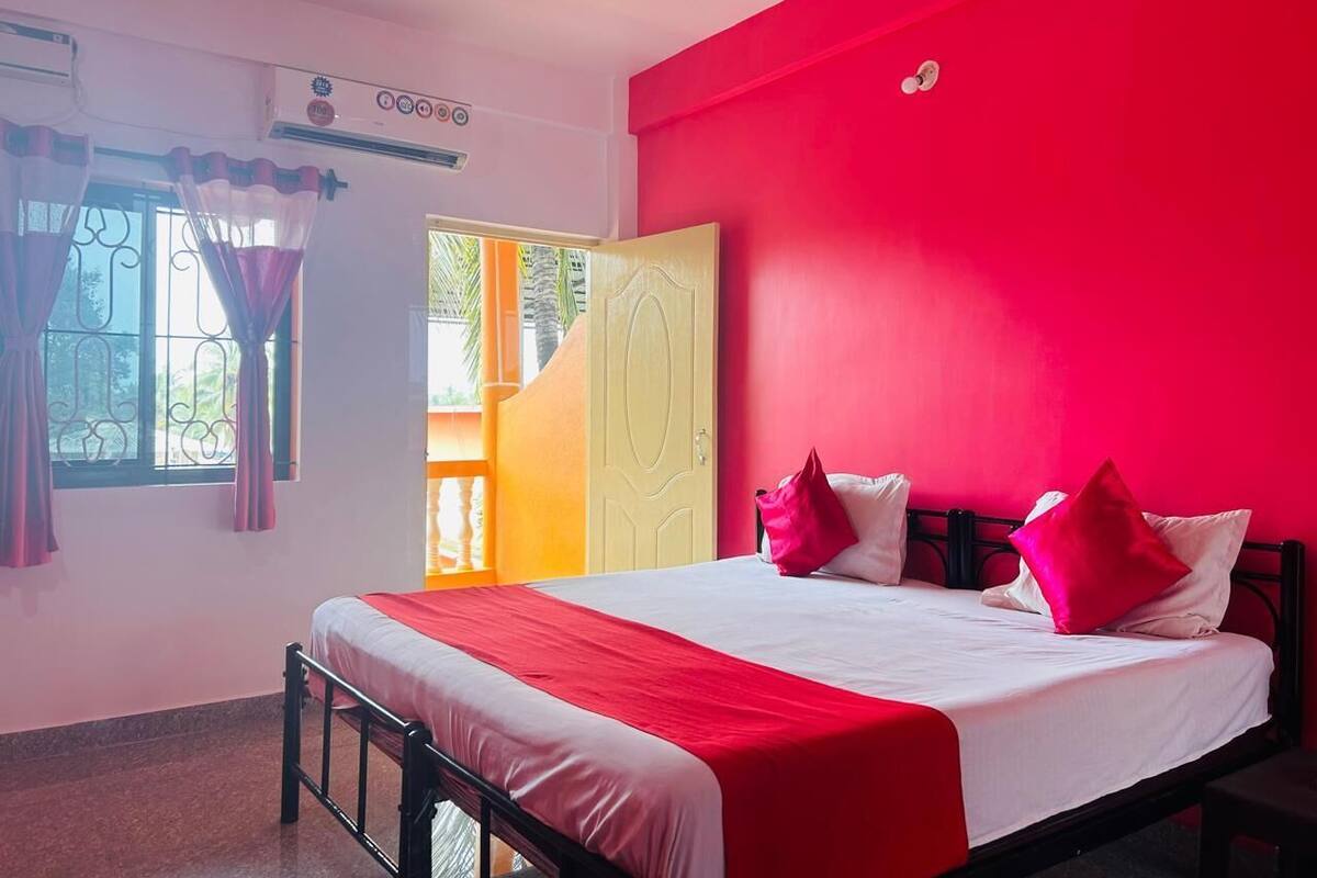 Quarto com cama, janela com cortinas e porta que dá para área externa.