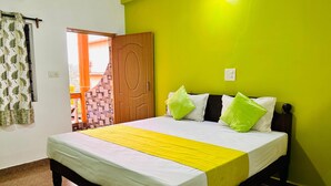 Una cama con ropa de cama blanca y amarilla, un cabecero de madera y almohadas verdes.