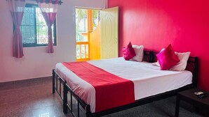Un dormitorio con cama, mesita de noche, ventana con cortinas y equipo de aire acondicionado.
