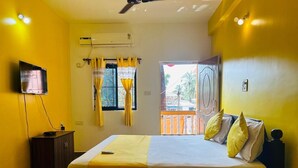 Habitación de hotel con cama, televisión, armario y ventana con cortinas.