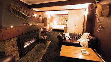 A cozy room with a fireplace, leather sofa, and a bed with a heart-shaped light decoration.