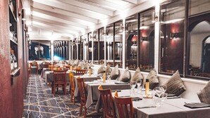 A restaurant with long tables, chairs, and a patterned carpet.