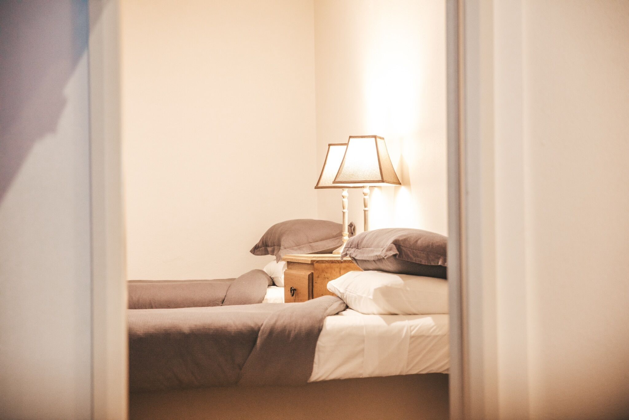 A bedroom with two single beds, a nightstand with a lamp, and a dresser.