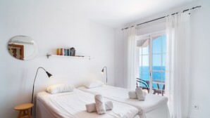 A hotel room with two beds, a small stool, a bedside table, a mirror, and a view of the sea through large windows. - Villa Prime Seaview by Casasol (Nerja)