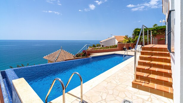 A swimming pool with a view of the ocean, steps leading to a building, and a tiled patio area. - Villa Prime Seaview by Casasol (Nerja)