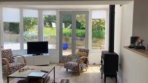 A living room with a television, a sofa, a coffee table, and a fireplace. - Charming house 3 kms from Caen.  Comfort, light, location -> Coup de coeur! (Fleury-sur-Orne)