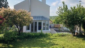 A modern house with a large glass window, a chimney, and a garden with various plants. - Charming house 3 kms from Caen.  Comfort, light, location -> Coup de coeur! (Fleury-sur-Orne)